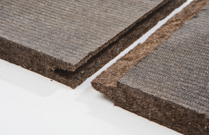 Två bruna, rektangulära skivor av fibermaterial med ruff yta och varierande tjocklek, liggande bredvid varandra på vit yta.