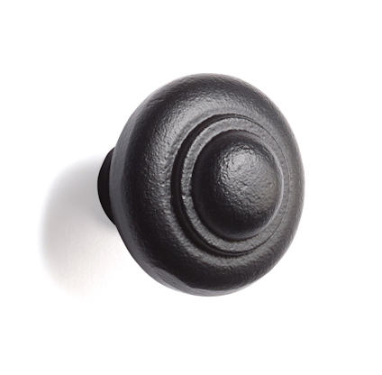 Svart rundad metallknopp med flera koncentriska cirklar.